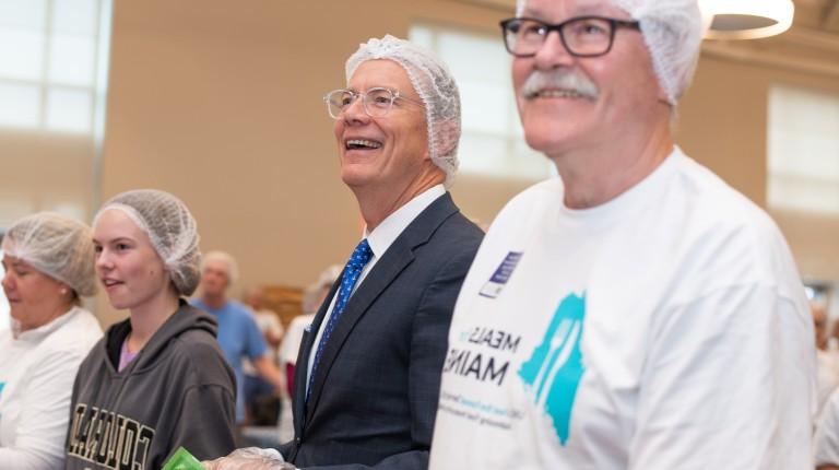 UNE President James Herbert smiles while helping pack meals at the Meals for Maine event