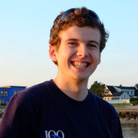 Andy Robinson stands on a beach smiling at the camera